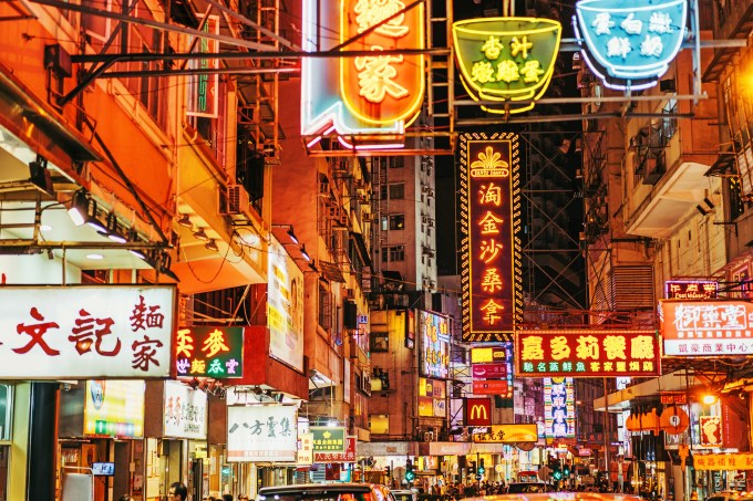 Rua comercial Kowloon, Hong Kong, na Ásia, com lojas e placas em neon