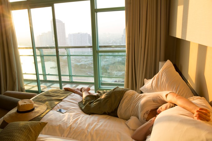 Mulher tenta dormir em quarto de hotel em Bangcoc, na Tailandia, durante o dia por jet lag