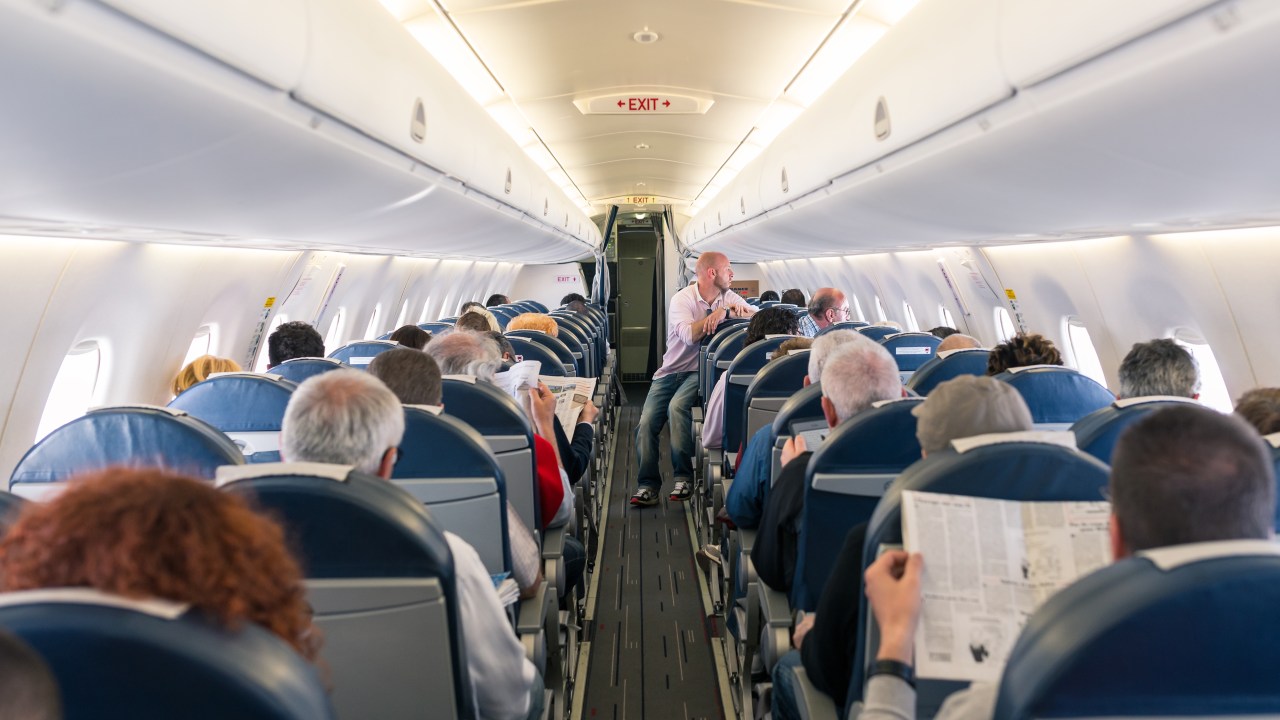 Cabine de um voo comercial de avião da Air France com passageiros a bordo lendo jornal