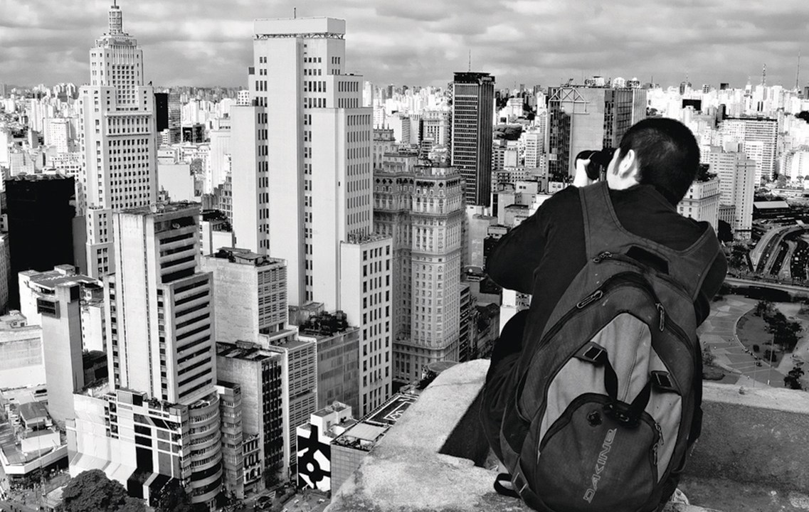 Homem fotografa o centro da cidade de São Paulo do alto de um prédio