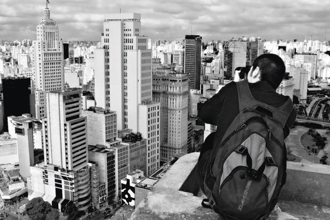 Homem fotografa o centro da cidade de São Paulo do alto de um prédio