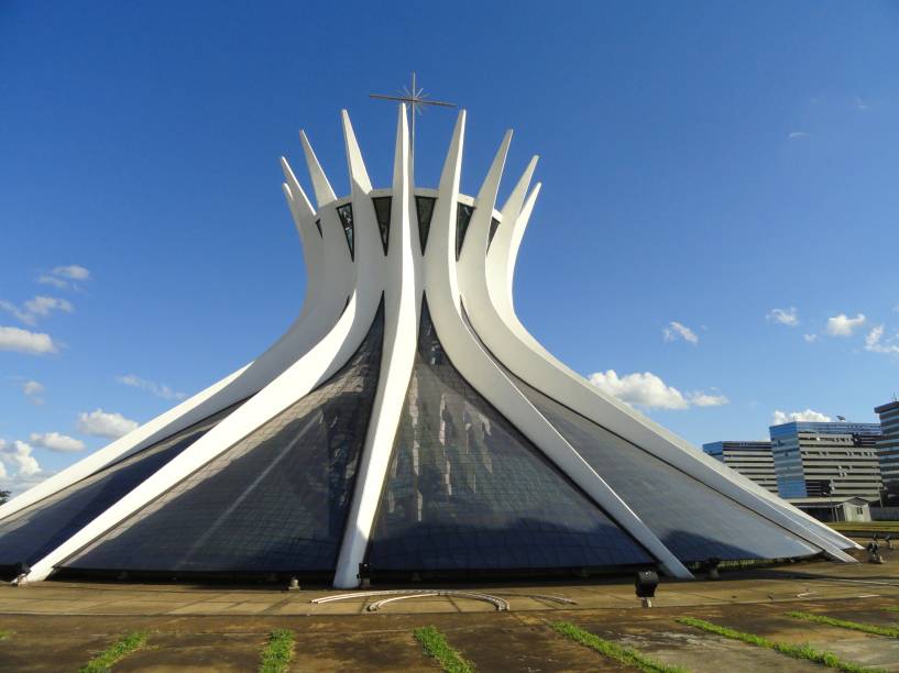 <a href="https://viajeaqui.abril.com.br/estabelecimentos/br-df-brasilia-atracao-catedral-metropolitana" rel="1. Catedral Metropolitana"><strong>1. Catedral Metropolitana</strong></a><a href="https://viajeaqui.abril.com.br/estabelecimentos/br-df-brasilia-atracao-catedral-metropolitana" rel="1. Catedral Metropolitana"><strong> </strong></a>Dedicada a Nossa Senhora Aparecida, a catedral projetada por Oscar Niemeyer foi o primeiro monumento a ser criado em Brasília e é também o primeiro da lista de melhores atrações da cidade segundo o Trip Advisor. Ela tem dezesseis colunas de concreto em formato de hipérbole, que fazem parecer que a estrutura é uma coroa.  Quatro esculturas de bronze de três metros de altura, criados por Dante Croce, representam os quatro evangelistas. O campanário em forma de T tem quatro sinos presenteados pelo governo espanhol. A cúpula do batistério, a cúria metropolitana e um espelho d’água completam o conjunto, que é facilmente reconhecível assim que o turista chega ao Plano Piloto de Brasília