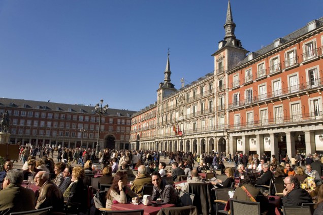Sob as arcadas da Plaza Mayor de Madri, do século 17, espalham-se mesinhas de diversos bares e cafés