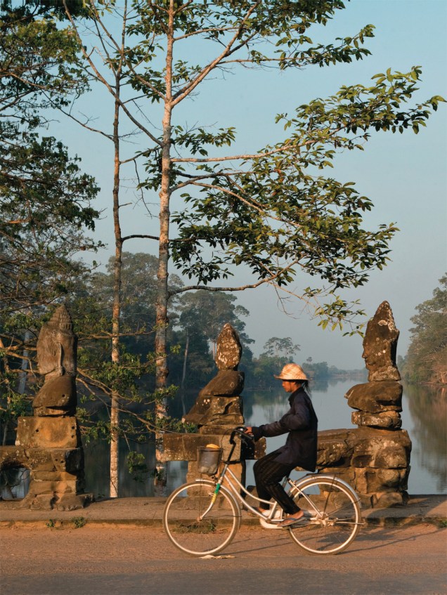 Ciclista na ponte que dá acesso à cidadela de Angkor Thom, no Camboja
