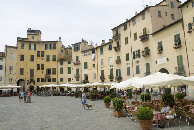A forma ovalada da Piazza Anfiteatro, em <a href="http://viajeaqui.abril.com.br/cidades/italia-lucca" rel="Lucca">Lucca</a>, é emoldurada por antigos prédios de fachadas em tons pastéis e agradáveis cafés