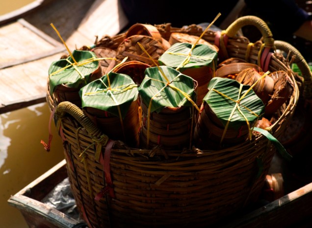 Abaixo o plástico! Vendedores de comida no mercado flutuante de Damnoen Saduak envolvem seus preparos em caixinhas de bambu, embalados em folhas de bananeira: bonito, sustentável e funcional
