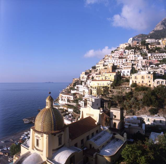 Vista da orla do vilarejo de <a href="http://viajeaqui.abril.com.br/cidades/italia-positano" rel="Positano">Positano</a>, na Costa Amalfitana, com a cúpula de cerâmica da Igreja Santa Maria Assunta em primeiro plano