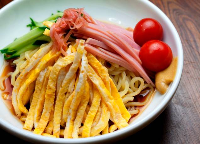 <strong>Hiyashi Chuka</strong>        O verão japonês às vezes pode ser opressor, com a umidade e calor chegando a níveis impensáveis. Para refrescar mentes e alegrar o estômago, pratos refrescantes pipocam nos cardápios dos restaurantes de todo o Japão. Uma das opções certeiras (e saudáveis) é o macarrão frio hiyashi chuka, coberto de tiras de omelete, carnes e verduras