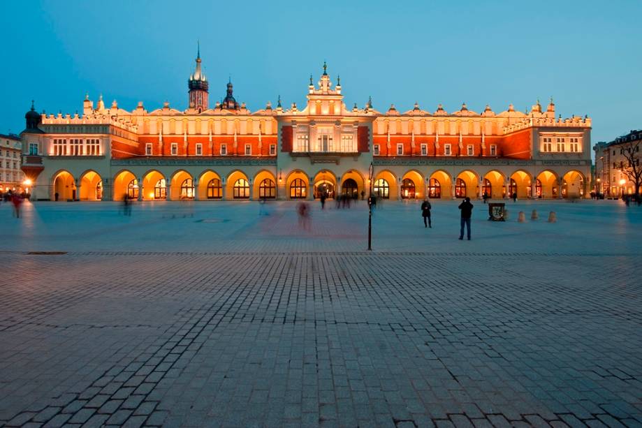 <strong>Praça do Mercado (Rynek Glówny) – <a href="https://viagemeturismo.abril.com.br/cidades/cracovia/" target="_blank" rel="noopener">Cracóvia</a> – <a href="https://viagemeturismo.abril.com.br/paises/polonia-2/" target="_blank" rel="noopener">Polônia</a></strong> O ponto focal de Cracóvia é sua grande Praça do Mercado. Em seu entorno encontram-se algumas das melhores opções de hospedagem da cidade, além de ótimos restaurantes, cafés e bares. Além disso, aqui estão o Sukiennice (Grande Salão das Guildas), à direita, onde hoje os turistas podem adquirir lembranças variadas, e a colorida e ricamente decorada Basílica de Santa Maria. Esta é a maior praça da Europa, declarada Patrimônio da Humanidade pela Unesco <em><a href="https://www.booking.com/searchresults.pt-br.html?aid=332455&sid=d98f25c4d6d5f89238aebe98e11a09ba&sb=1&src=searchresults&src_elem=sb&error_url=https%3A%2F%2Fwww.booking.com%2Fsearchresults.pt-br.html%3Faid%3D332455%3Bsid%3Dd98f25c4d6d5f89238aebe98e11a09ba%3Btmpl%3Dsearchresults%3Bac_click_type%3Db%3Bac_position%3D0%3Bcity%3D-129709%3Bclass_interval%3D1%3Bdest_id%3D-345275%3Bdest_type%3Dcity%3Bdtdisc%3D0%3Bfrom_sf%3D1%3Bgroup_adults%3D2%3Bgroup_children%3D0%3Biata%3DCUZ%3Binac%3D0%3Bindex_postcard%3D0%3Blabel_click%3Dundef%3Bno_rooms%3D1%3Boffset%3D0%3Bpostcard%3D0%3Braw_dest_type%3Dcity%3Broom1%3DA%252CA%3Bsb_price_type%3Dtotal%3Bsearch_selected%3D1%3Bshw_aparth%3D1%3Bslp_r_match%3D0%3Bsrc%3Dsearchresults%3Bsrc_elem%3Dsb%3Bsrpvid%3D18f97cc4163f00ab%3Bss%3DCusco%252C%2520Cusco%252C%2520Peru%3Bss_all%3D0%3Bss_raw%3Dcusco%3Bssb%3Dempty%3Bsshis%3D0%3Bssne%3DSiena%3Bssne_untouched%3DSiena%26%3B&ss=Crac%C3%B3via%2C+Lesser+Poland%2C+Pol%C3%B4nia&is_ski_area=&ssne=Cusco&ssne_untouched=Cusco&city=-345275&checkin_year=&checkin_month=&checkout_year=&checkout_month=&group_adults=2&group_children=0&no_rooms=1&from_sf=1&ss_raw=crac%C3%B3via&ac_position=0&ac_langcode=xb&ac_click_type=b&dest_id=-510625&dest_type=city&iata=KRK&place_id_lat=50.063&place_id_lon=19.937&search_pageview_id=18f97cc4163f00ab&search_selected=true&search_pageview_id=18f97cc4163f00ab&ac_suggestion_list_length=5&ac_suggestion_theme_list_length=0" target="_blank" rel="noopener">Busque hospedagem em Cracóvia</a> </em>