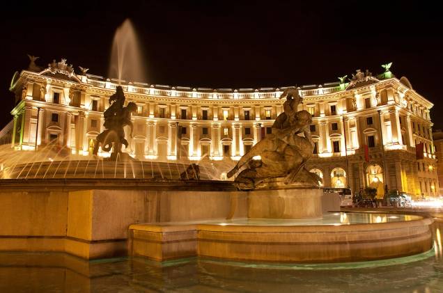 Os prédios dos hotéis iluminados ao redor da Piazza della Republica, na noite de <a href="http://viajeaqui.abril.com.br/cidades/italia-roma" rel="Roma">Roma</a>, dão um charme ao lugar