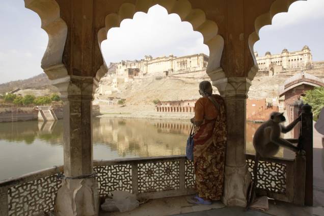 Mulher avista ao longe as poderosas muralhas do Forte Amber, em Jaipur, na Índia