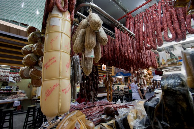 As linguiças artesanais e queijos gigantes, como este provolone com mais de um metro de altura da Galeria do Bacalhau, também estão entre as delícias vendidas nas lojas do Mercadão