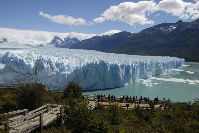 Na passarela de madeira, os visitantes veem os blocos que se desprendem da Geleira Perito Moreno e caem no Lago Argentino, produzindo sons ensurdecedores