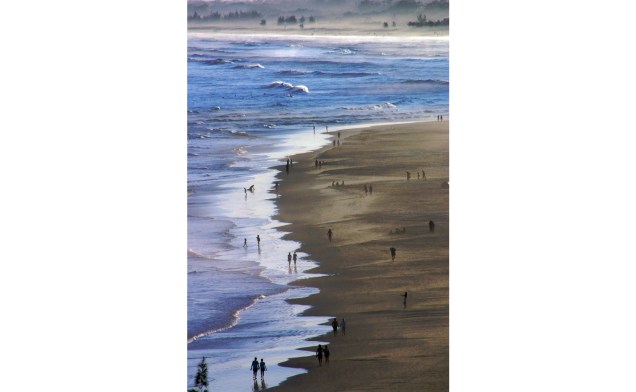 Pessoas caminham pela praia da Ferrugem, em Garopaba, Santa Catarina