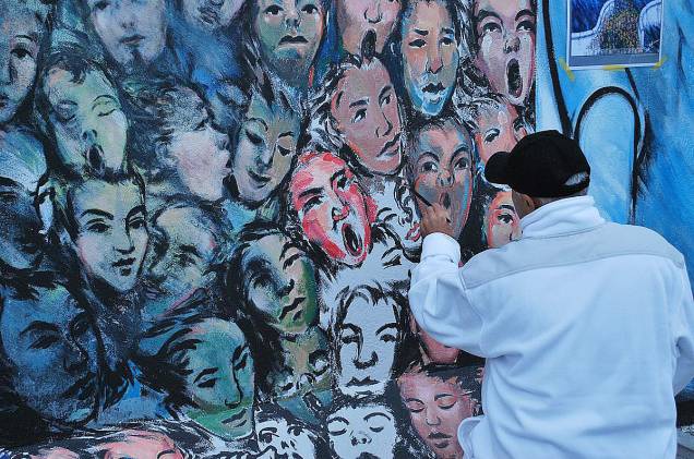 Artista retocando sua obra no muro Artista retocando sua obra no muro