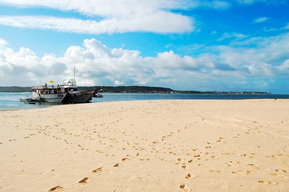 Em um canto da praia estão barracas com serviço de praia e em outro pouco movimento com falésias coloridas