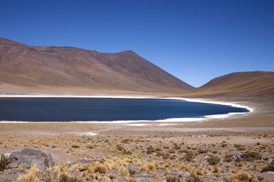 O contraste entre as cores da areia, a rala vegetação, as águas verdes das lagoas Meñiques e Miscanti e os picos nevados ao fundo são um convite à meditação