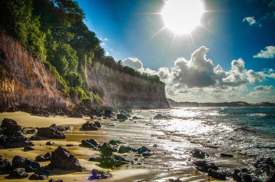 Na maré alta, a faixa de areia quase some entre o mar e as falésias