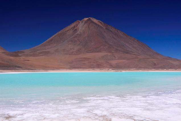 Localizado a 4000 metros de altitude, a Laguna Verde possui esse tom por conta de traços de cobre oxidados. O vulcão Licanbur é um dos muitos que pontilham o altiplano boliviano