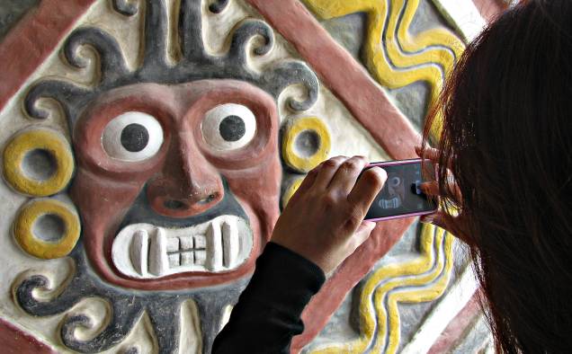 Turista fotografa a imagem do deus moche Ai-apaec em um templo do complexo de El Brujo