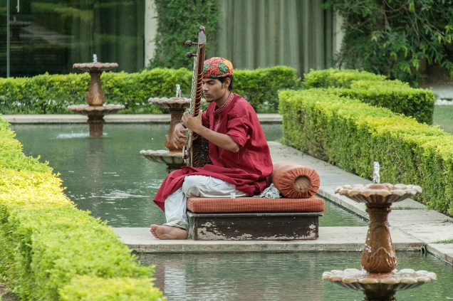 Um músico toca a cítara enquanto os hóspedes meditam no jardim do hotel Rambagh Palace, em Jaipur