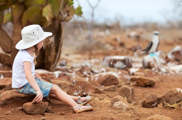 Menina observa pássaro na ilha de Galápagos, Equador