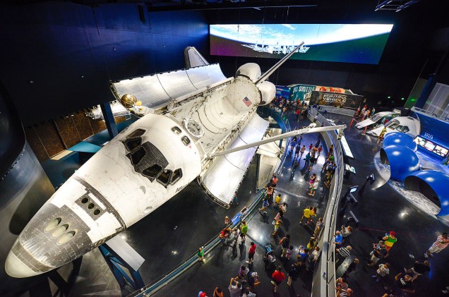 Visitantes admiram o ônibus espacial Atlantis, em exibição com os braços mecânicos que consertaram o telescópio Hubble em 2009
