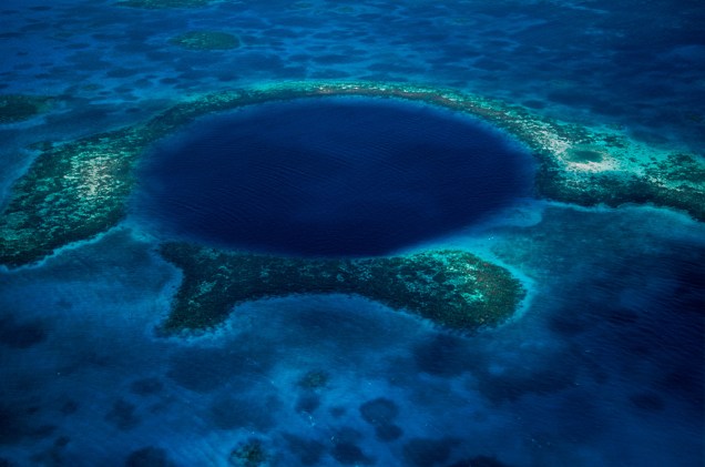 <strong>Blue Hole, Belize</strong>300 metros de diâmetro e 135 metros de profundidade são as assustadoras e maravilhosas medidas desse buraco no atol Lighthouse Reef. Circundado por um recife, é um verdadeiro paraíso para os mergulhadores que procuram uma rica vida marina (tubarões gigantes, peixes e arraias) e formações espetaculares (enormes estalactites e estalagmites), e também uma fonte para os curiosos de plantão. Ele foi formado durante a Era Glacial, quando o nível do mar estava mais baixo. Ao esquentar, o gelo derreteu, as águas subiram e encheram a abertura