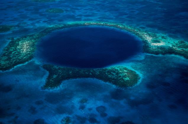 <strong>Belize </strong>Localizado no nordeste da <a href="http://viajeaqui.abril.com.br/continentes/america-central" rel="América Central" target="_blank">América Central</a>, as águas cristalinas e o ecossistema formado por peixes de cores variadas, golfinhos, arraia-mantas (arraias mantas são uma das maiores do mundo), pequenos tubarões, manguezais, atóis e a maior barreira de corais do Hemisfério Norte – com 298 km de extensão - fazem do local um dos pontos procurados para mergulho. Mas é o famoso “Blue Hole” (foto), no centro do atol Lighthouse Reef, a verdadeira obra-prima de Belize. Trata-se de uma circunferência escavada pela natureza no meio da barreira de corais, com mais de 300 metros de diâmetro e 135 metros de profundidade, onde mergulhadores experientes encontram enormes estalactites e estalagmites, algumas com mais de cinco metros de comprimento. A melhor época para mergulhar em Belize está entre os meses de abril e junho. Os principais pontos de mergulho são as ilhas Turneffe, o Lighthouse Reef, o Atol de Glover e Ambergris Cave. A vantagem para o visitante é que o turismo se estruturou para os interessados em mergulho e são diversos resorts e agências especializadas na modalidade. As temperaturas altas, com média de 29°C, incentivam ainda mais os passeios aquáticos e são responsáveis pela rica vida marinha de Belize. A língua oficial dos moradores locais é o inglês e a moeda é o dólar de Belize.
