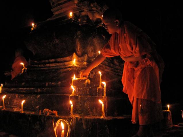 Aprendiz de monge acende vela durante o FEstiva Boun Ok Phansa, em Luang Prabang