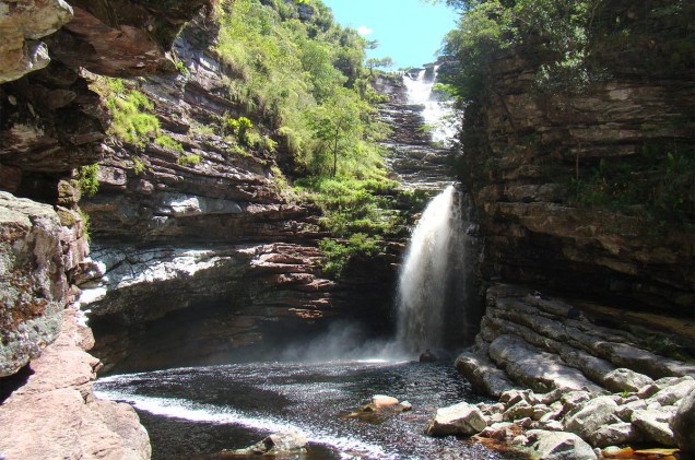 A água da cachoeira desliza por uma escadinha natural e cai num poço