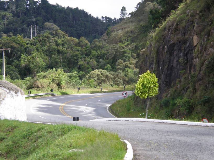 <strong>ACESSO</strong> - <strong>Campos do Jordão vence!</strong><br /><br />Há três maneiras de se chegar em Campos do Jordão, mas 95% dos visitantes sobem a Serra da Mantiqueira pela Rodovia Floriano Rodrigues Pinheiro (foto). Então vamos nos ater a ela. Entre o trevo da Via Dutra, em <a href="https://viajeaqui.abril.com.br/cidades/br-sp-taubate" rel="Taubaté" target="_blank">Taubaté</a> até a entrada de Campos do Jordão são 48 quilômetros divididos quase que irmanamente entre o trecho de planalto e serra. Nessa primeira perna, é recomendado um pit stop no Leite na Pista – enquanto os adultos compram queijos e bolo de tapioca, as crianças se divertem com o laguinho e os animais no gramado. A subida da serra é bem tranquila, com terceira pista e a vista de um belo vale. Na metade da subida, outro interessante ponto de parada: na estação ferroviária Eugênio Lefèvre, virou tradição provar o bolinho de bacalhau servido na lanchonete. Já no alto da serra, o Belvedere oferece uma vista espetacular tendo o Pico Agudo, em Santo Antônio do Pinhal, a Pedra do Baú e o Vale do Paraíba como protagonistas.<br /><br />Chegar em Monte Verde não suscita grandes emoções. Já é muito bom saber da pavimentação dos 33 quilômetros da estradinha que liga Camanducaia a Monte Verde. A subida é meio travada e a pista, estreita. Apenas nos 10 quilômetros finais a vista fica mais abrangente e consegue-se observar as famosas montanhas da vila (Pico do Selado, Pedra Vermelha e Pedra Redonda) e as araucárias que dão um charme todo especial à vila .