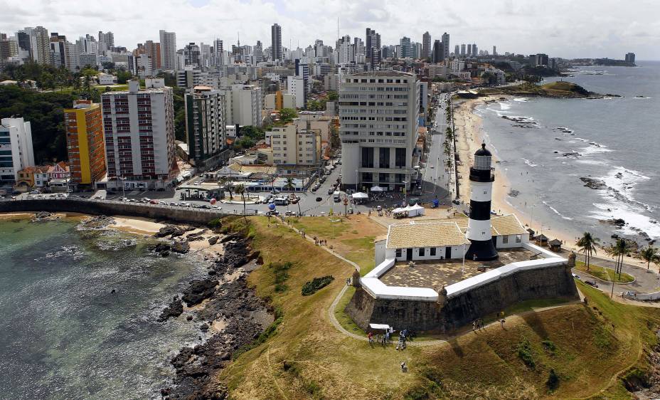 Turistas fotografam o <a href="https://viajeaqui.abril.com.br/estabelecimentos/br-ba-salvador-atracao-de-santo-antonio-da-barra-farol-da-barra" rel="Farol da Barra de Salvador (BA)" target="_blank">Farol da Barra,</a> em <a href="https://viajeaqui.abril.com.br/cidades/br-ba-salvador" rel="Salvador (BA)" target="_blank">Salvador (BA)</a>; o local é ótimo para vislumbrar o por do sol na capital baiana