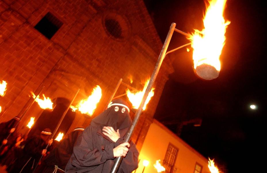 Um farricoco (fiel encapuzado) carrega uma tocha durante a Procissão do Fogaréu, em Guimarães, Portugal. A celebração dramatiza a perseguição e prisão de Cristo, às 0h da quinta-feira santa