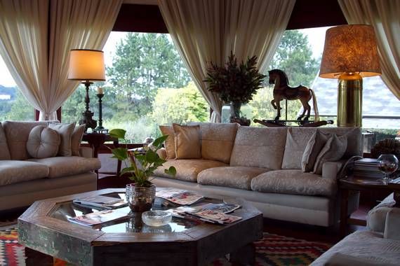 A sala de estar do Chateau La Villette, em Campos do Jordão, possui vista panorâmica para o jardim e montanhas