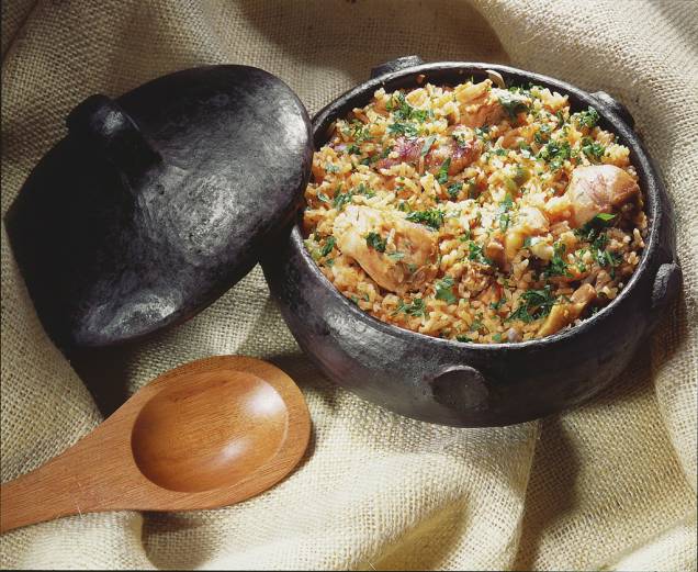 <strong>Galinhada</strong> Servida, geralmente, em eventos especiais, é um arroz reforçado com pedaços de frango caipira. A mistura costuma ser refogada com pequi e cúrcuma e, por isso, ganha coloração alaranjada.