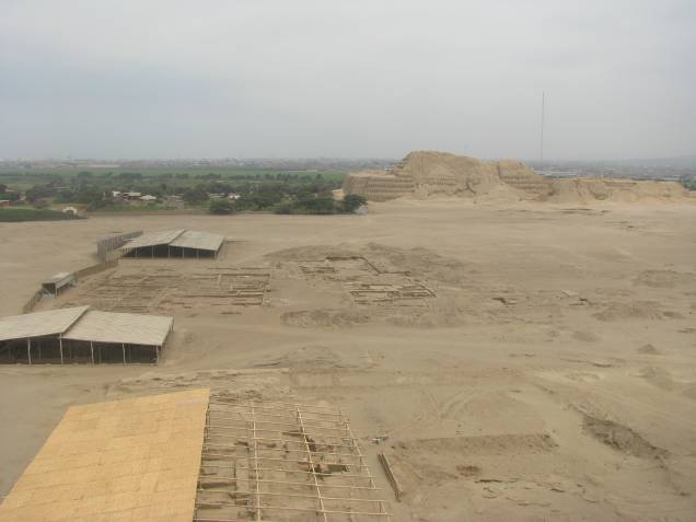 Vista a partir da Huaca de la Luna: vestígios de ruas, avenidas, casas e praças que formavam a cidade dos moches, com a Huaca del Sol ao fundo (atrás os campos de cana de açúcar que cercam Trujillo) Vista a partir da Huaca de la Luna: vestígios de ruas, avenidas, casas e praças que formavam a cidade dos moches, com a Huaca del Sol ao fundo (atrás os campos de cana de açúcar que cercam Trujillo)