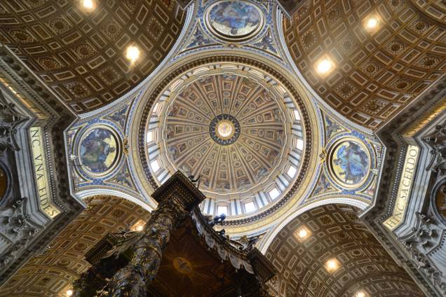 Cúpula da Basílica de São Pedro, sobre o Baldaquino de Bernini. As cabeças dos evangelistas, nos medalhões entre as colunas, têm mais de 1,5 metro de comprimento