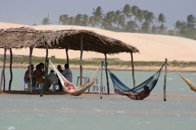 Turistas se refrescam no quiosque e nas redes dentro do mar na praia de Tatajuba, perto de Jericoacoara