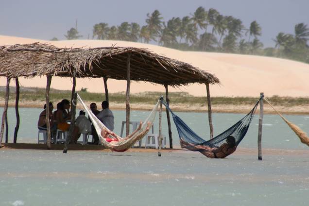 Turistas se refrescam no quiosque e nas redes dentro do mar na praia de Tatajuba, em Camocim, perto de Jericoacoara