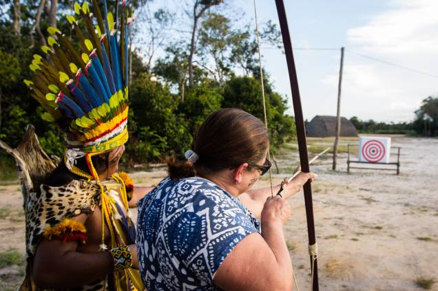 Além de vestir-se, pintar-se e comer como os indígenas, os turistas também têm aulas de arco-e-flecha tradicional da etnia.