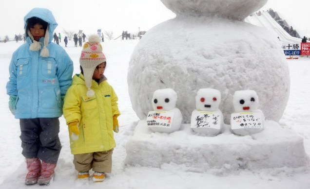 Crianças fazendo pose junto a bonecos de neve no Festival da Neve de Sapporo, o <em>Yuki Matsuri</em>