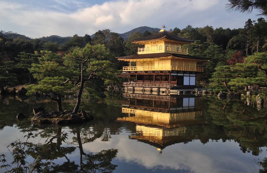 <strong>Kinkaku-ji (Rokuon-ji) </strong> Apelidado de “pavilhão dourado”, é com certeza uma das construções mais bonitas da cidade. Antiga “casa de repouso” do shogun (antigo chefe de estado) Ashikaga Yoshimitsu, foi transformado em templo budista após sua morte em 1408. Com os dois andares superiores inteiramente revestidos por folhas de ouro, o pavilhão literalmente brilha ao refletir a luz do sol, e tem o efeito maximizado pelo reflexo no lago a sua volta. A construção já foi destruída por dois incêndios, mas foi reconstruída a cada vez – a estrutura atual data de 1955. <strong>Kinkaku-ji (Rokuon-ji) </strong> Apelidado de “pavilhão dourado”, é com certeza uma das construções mais bonitas da cidade. Antiga “casa de repouso” do shogun (antigo chefe de estado) Ashikaga Yoshimitsu, foi transformado em templo budista após sua morte em 1408. Com os dois andares superiores inteiramente revestidos por folhas de ouro, o pavilhão literalmente brilha ao refletir a luz do sol, e tem o efeito maximizado pelo reflexo no lago a sua volta. A construção já foi destruída por dois incêndios, mas foi reconstruída a cada vez – a estrutura atual data de 1955.