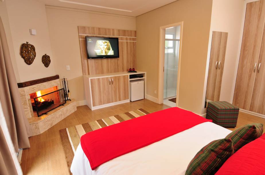 A suíte premium da Annecy Pousada, em Campos do Jordão, tem cama king-size, lareira e hidro