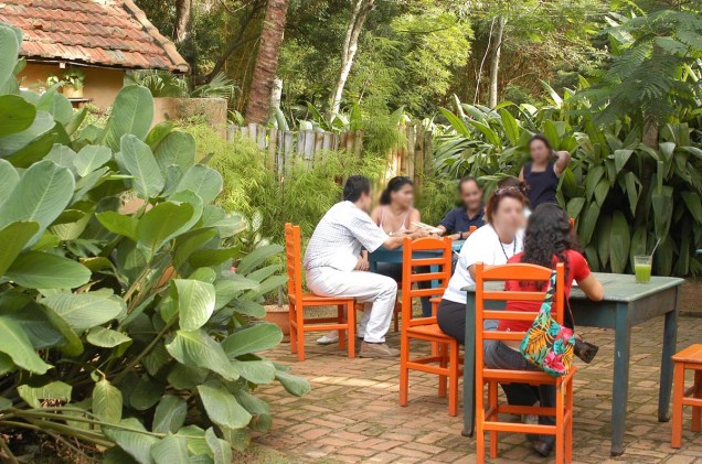 Mesas dispostas no jardim da casa oferecem tranquilidade aos clientes