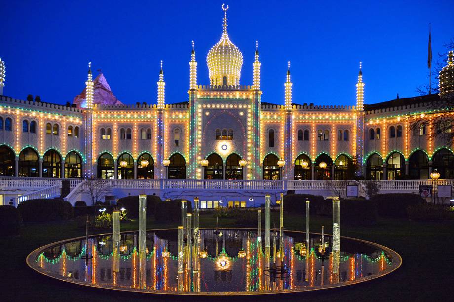 A fachada do hotel Nimb, que fica dentro do <a href="https://viajeaqui.abril.com.br/estabelecimentos/dinamarca-copenhague-atracao-tivoli" rel="Tivoli" target="_blank">Tivoli</a>, fica toda iluminada à noite – assim como os outros edifícios do parque