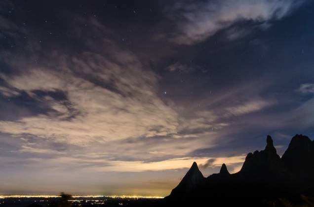 Vista de Teresópolis à noite, com a silhueta de seu ponto turístico mais famoso: o Dedo de Deus