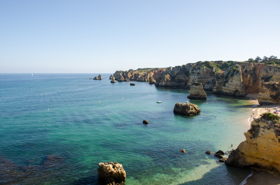 Apesar de pequena, com apenas 40 metros de largura, é considerada por muitos a mais bela praia do mundo! Além disso, é superfrequentada por turistas graças às suas águas calmas e transparentes e ao pouco vento que bate na sua costa. Grande parte da sua beleza deve-se ao fato dela se localizar na Costa DOiro, região onde as rochas têm tonalidades douradas. A mistura de tons (azul turquesa da água, azul do céu e amarelo das pedras) é o grande atrativo da praia. <a href="https://www.booking.com/landmark/pt/praia-da-dona-ana.html?aid=332455&label=viagemabril-praiasportugal" target="_blank" rel="noopener noreferrer"><em>Reserve o seu hotel na Praia da Dona Ana através do Booking.com</em></a>