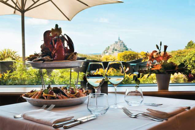 <strong>PAISAGEM INSÓLITA</strong> Mesa de frutos do mar com vista para o Mont Saint-Michel, península que vira ilha na maré alta <strong>PAISAGEM INSÓLITA</strong> Mesa de frutos do mar com vista para o Mont Saint-Michel, península que vira ilha na maré alta