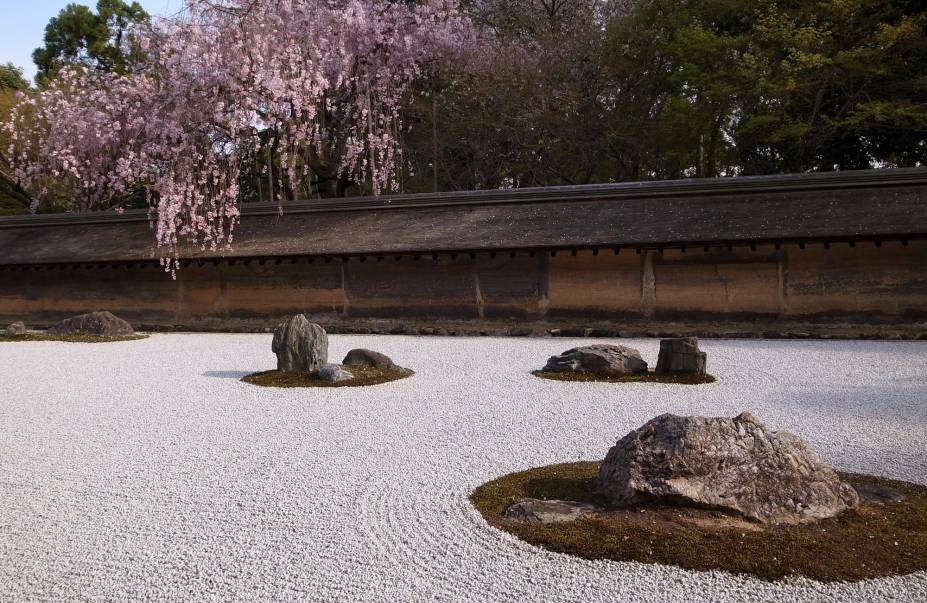 <strong>Ryoan-ji </strong> Localizado na parte nordeste da cidade, o templo também é Patrimônio Mundial da Humanidade pela UNESCO e tem destaque para seu jardim de pedras, o mais famoso do Japão. Apesar de sua história e significado não serem claros, o jardim é considerado uma obra prima desta forma de arte japonesa, que vem do zen budismo: as pedras são cuidadosamente arranjadas em um terreno forrado de cascalho com linhas desenhadas, criando um design que deve reproduzir a essência da natureza e ajudar na meditação zazen. Neste jardim, 15 pedras foram posicionadas de tal maneira que não importa a partir de que ponto se olha, somente 14 serão visíveis. Reza a lenda que só é possível avistar todas as pedras ao mesmo tempo quando o praticante do zen budismo atingir o nirvana. <strong>Ryoan-ji </strong> Localizado na parte nordeste da cidade, o templo também é Patrimônio Mundial da Humanidade pela UNESCO e tem destaque para seu jardim de pedras, o mais famoso do Japão. Apesar de sua história e significado não serem claros, o jardim é considerado uma obra prima desta forma de arte japonesa, que vem do zen budismo: as pedras são cuidadosamente arranjadas em um terreno forrado de cascalho com linhas desenhadas, criando um design que deve reproduzir a essência da natureza e ajudar na meditação zazen. Neste jardim, 15 pedras foram posicionadas de tal maneira que não importa a partir de que ponto se olha, somente 14 serão visíveis. Reza a lenda que só é possível avistar todas as pedras ao mesmo tempo quando o praticante do zen budismo atingir o nirvana.